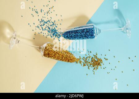 Zwei Weingläser mit buntem, glänzendem Lametta-Hintergrund, Draufsicht. Party Inspiration flach Lay Stockfoto