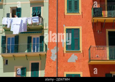 Camogli, Italien - 10. Juni 2022: Frau hängt saubere Wäsche, um sie in der Sonne zu trocknen im mediterranen Dorf Camogli, Italien. Stockfoto