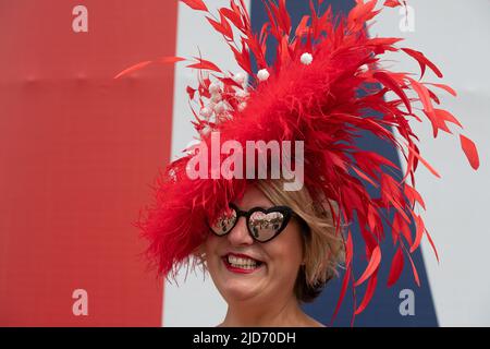 Ascot, Bergen, Großbritannien. 18.. Juni 2022. Milliner Sally Harper trägt einen ihrer roten Kopfbedeckungen. Racegoers, die in Royal Ascot ankamen, sahen für den letzten Tag von Royal Ascot sehr glamourös aus. Nach einer Woche strahlenden Sonnenlichtes gab es heute Morgen ein paar Regenstellen, so dass die Regenschirme eine Weile in Aktion waren. Quelle: Maureen McLean/Alamy Live News Stockfoto