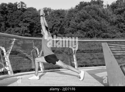 Fit Mann halten virabhadrasana Pose tun Halbmond Ausfallschritt Strecke auf Promenade, Yoga Stockfoto