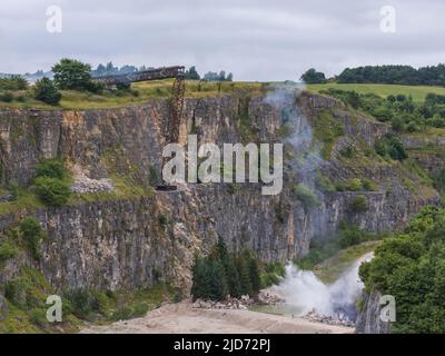 ***Video verfügbar*** Mission: Impossible 7 Lokomotivzug-Crashszene in Stoney Middleton, Derbyshire. Der nachgebaute Dampfzug der British Railway Britannia wird für die letzte Crashszene in Tom Cruise's neuestem Blockbuster-Film von der Klippe getrieben. Die Lokomotive fliegt in spektakulärem Stil durch die Luft, bevor sie in den Steinbruch darunter stürzt. Die Szene wurde von zwei Hubschraubern und vielen entfernten Kameras gefilmt. Tom Cruise kam kurz vor der letzten Absturzszene in seinem Personalhubschrauber an, er flog um den Film, bevor er auf den Feldern in der Nähe der Eisenbahnstrecke über dem Steinbruch landete. Der Dampfstoß tr Stockfoto