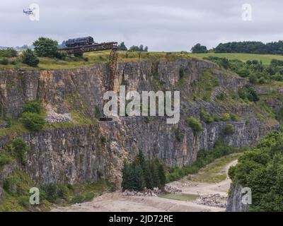 ***Video verfügbar*** Mission: Impossible 7 Lokomotivzug-Crashszene in Stoney Middleton, Derbyshire. Der nachgebaute Dampfzug der British Railway Britannia wird für die letzte Crashszene in Tom Cruise's neuestem Blockbuster-Film von der Klippe getrieben. Die Lokomotive fliegt in spektakulärem Stil durch die Luft, bevor sie in den Steinbruch darunter stürzt. Die Szene wurde von zwei Hubschraubern und vielen entfernten Kameras gefilmt. Tom Cruise kam kurz vor der letzten Absturzszene in seinem Personalhubschrauber an, er flog um den Film, bevor er auf den Feldern in der Nähe der Eisenbahnstrecke über dem Steinbruch landete. Der Dampfstoß tr Stockfoto