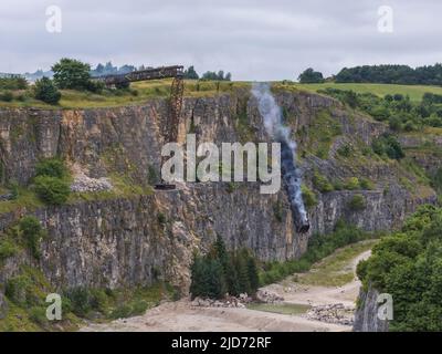 ***Video verfügbar*** Mission: Impossible 7 Lokomotivzug-Crashszene in Stoney Middleton, Derbyshire. Der nachgebaute Dampfzug der British Railway Britannia wird für die letzte Crashszene in Tom Cruise's neuestem Blockbuster-Film von der Klippe getrieben. Die Lokomotive fliegt in spektakulärem Stil durch die Luft, bevor sie in den Steinbruch darunter stürzt. Die Szene wurde von zwei Hubschraubern und vielen entfernten Kameras gefilmt. Tom Cruise kam kurz vor der letzten Absturzszene in seinem Personalhubschrauber an, er flog um den Film, bevor er auf den Feldern in der Nähe der Eisenbahnstrecke über dem Steinbruch landete. Der Dampfstoß tr Stockfoto