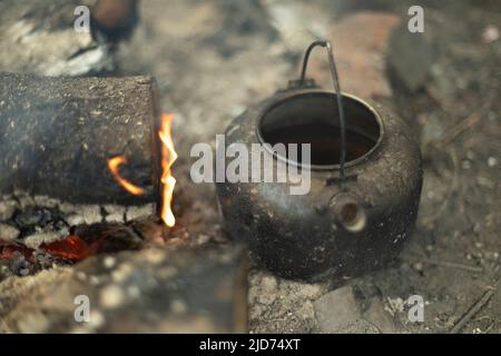 Wasserkocher für Tee am Feuer. Tee in der Natur. Erhitzen von Wasser im Feuer. Stockfoto