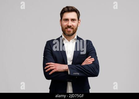 Positiver männlicher Business Coach im klassischen Anzug mit gekreuzten Händen und Blick auf die Kamera Stockfoto