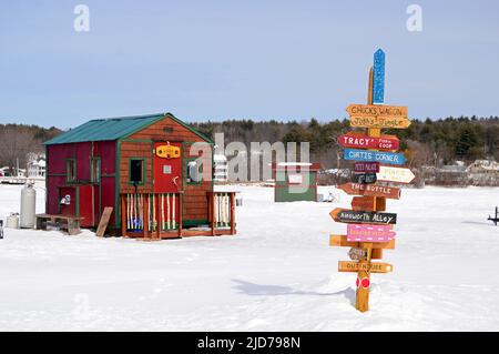 Schilder weisen den Weg zu einer Vielzahl von Eisfischen Hütten am Lake Winnipesaukee Stockfoto