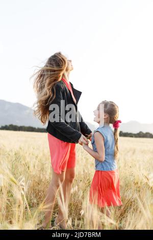 Spaß für die ganze Familie. Mutter und Tochter springen auf dem Feld Stockfoto