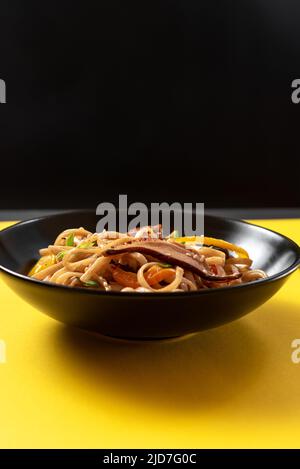 Teller mit Nudeln auf hellgelbem Hintergrund. Stockfoto