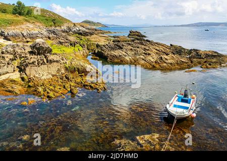 Kleines Motorboot neben den Felsen des Meeres mit transparentem Wasser. Stockfoto