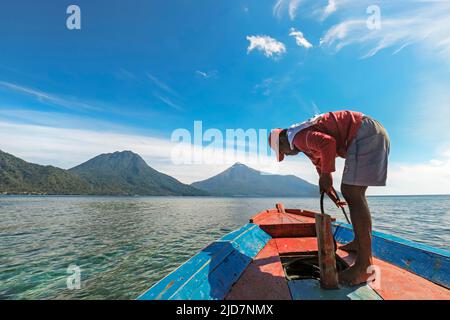 Bootstour Kapitän vor Siau mit Buhias Island & Karangetang Vulkan dahinter. Siau Island, Sangihe Archipel, Nord-Sulawesi, Indonesien Stockfoto