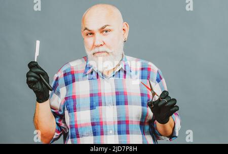 Mann mittleren Alters, Friseur hält Friseur Ausrüstungen, isoliert auf grauem Hintergrund. Friseurladen Barbershop Konzept. Haarbehandlung für Männer. Stockfoto