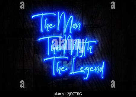 Der Mann, der Mythos, die Legende, das blaue Neon-Zeichen auf einer dunklen Holzwand Stockfoto