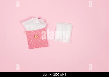 Damenbinden und rosa Handtasche auf rosa Hintergrund. Hygienische Pflege an kritischen Tagen. Menstruationszyklus. Gesundheitsversorgung für Frauen. Monatlicher Schutz Stockfoto