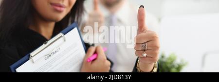 Schöne Frau hält einen Vertrag und zeigt ok Geste Stockfoto