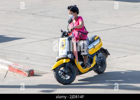 SAMUT PRAKAN, THAILAND, JUNI 10 2022, Eine Frau mit Gesichtsmaske fährt ein Motorrad Stockfoto