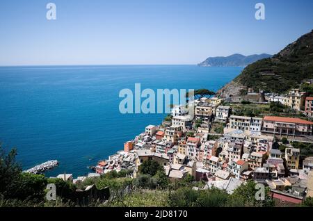 Riomaggiore, Ligurien, Italien - April, 2022: Panoramablick von oben auf ein kleines touristisches Dorf mit typisch italienischen Gebäuden in Cinque Terre Stockfoto