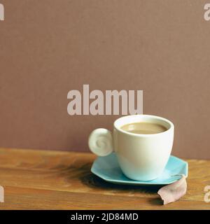 Tasse Kaffee auf Holztisch. Brauner Wandhintergrund Stockfoto