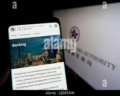 Person, die Mobiltelefon mit der Webseite der Hong Kong Monetary Authority (HKMA) auf dem Bildschirm vor dem Logo hält. Konzentrieren Sie sich auf die Mitte des Telefondisplays. Stockfoto