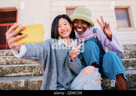 Zwei lächelnde Mädchen, die im Freien ein Selfie mit dem Smartphone machen Stockfoto