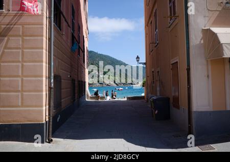 Sestri Levante, Ligurien, Italien - April, 2022: Zugang zum Meer, zum Strand und zur Bucht von Baia del Silenzio durch einen schmalen Durchgang zwischen zwei Wohngebäuden Stockfoto