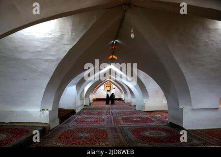 Gebetssaal für Frauen in der Freitsmoschee in Isfahan, Iran. Im Hintergrund sind zwei verhüllte Frauen sichtbar. The Boden is vollstndig with teppichen ausgelegt. Stockfoto