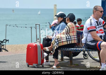 Brighton Großbritannien 19.. Juni 2022 - heute mittags haben sich Besucher in warme Kleidung an der Strandpromenade von Brighton eingewickelt, da sich nach der kürzlichen Hitzewelle in ganz Großbritannien kühleres Wetter ausbreitet. : Credit Simon Dack / Alamy Live News Stockfoto