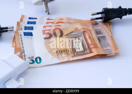 Steckdosen mit Euro-Banknoten auf weißem Hintergrund. Stockfoto