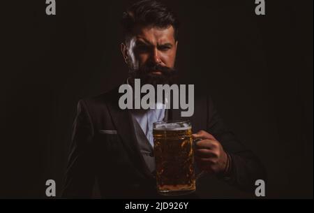 Porträt eines ernsthaften bärtigen Mannes, der Bier trinkt. Fröhlicher Brauer, der Glas mit Bier hält. Stockfoto