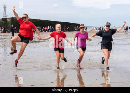 Thorpe Bay, Essex, Großbritannien. 19. Juni 2022. Ein Abschnitt des D-Day Mulberry Harbour aus dem Zweiten Weltkrieg wurde in der Themse-Mündung über eine Meile vor der Küste von Thorpe Bay in der Nähe von Southend on Sea nach Schwierigkeiten, als er 1944 unter Schlepptau lag, befahren und liegt seitdem dort. Es ist jetzt ein geplantes Denkmal und ist in zwei zerbrochen. Der riesige Phoenix Caisson ist bei Ebbe zu Fuß kurz erreichbar, obwohl viele von den RNLI gerettet werden mussten, wenn die Meerwasser zurückkehren. Der Wohltätigkeitslauf wurde sorgfältig geplant und überwacht, um die Läufer sicher zu halten, wobei der Erlös an die RNLI ging. Läufer auf Rücklaufstrecke Stockfoto