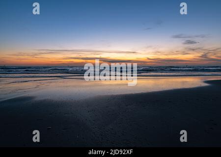 Wilder Himmel über der Nordsee während der kürzesten Nächte. Schöne Reflexionen von Farben im nassen Sand. Stockfoto