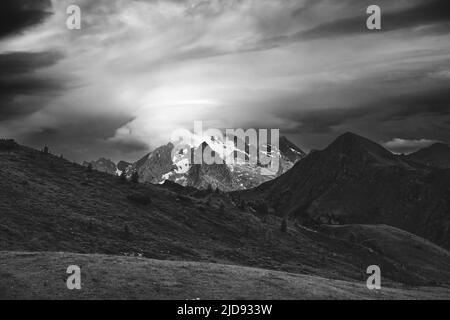 Sonnenlicht auf der Marmolada-Berggruppe. Sich bewegende Wolken. Dramatischer Himmel. Die Dolomiten. Italienische Alpen. Europa. Schwarz-weiße Landschaft. Stockfoto