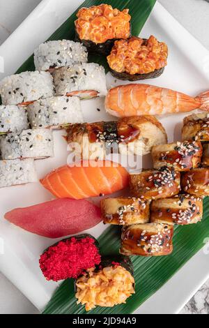 Set aus verschiedenen bunten Maki Sushi-Rollen, Nigiri und Gunkan mit Tiger Shrimps, tomago, Lachs, Thunfisch, chuka-Salat, Fliegender Fischkaviar, Thunfisch und Grün Stockfoto