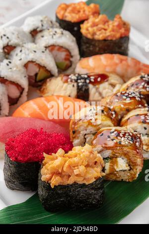 Set aus verschiedenen bunten Maki Sushi-Rollen, Nigiri und Gunkan mit Tiger Shrimps, tomago, Lachs, Thunfisch, chuka-Salat, Fliegender Fischkaviar, Thunfisch und Grün Stockfoto