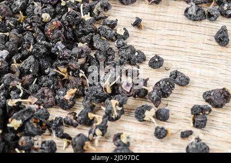 Die schwarzen Wolfbeeren oder schwarzen Goji-Beeren, auf Holzgrund. Stockfoto