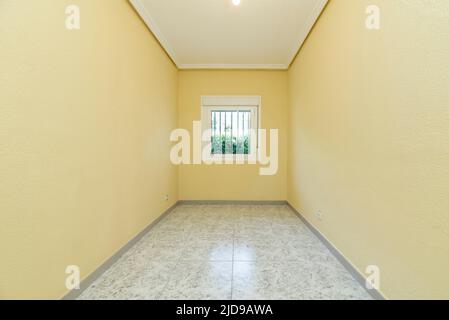 Leeres Schlafzimmer mit verbarrtem Fenster mit Blick auf den Garten Stockfoto