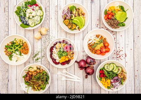 Set aus weißen Schalen voller vegetarischer Salate aller Art, frisch, energiespendend und gesund Stockfoto