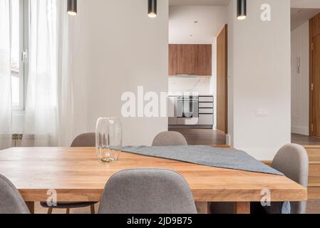 Esstisch aus Naturholz in einem Wohnzimmer im Dachgeschoss mit Holztreppen und Zugang zu einer offenen Küche mit Holzmöbeln Stockfoto