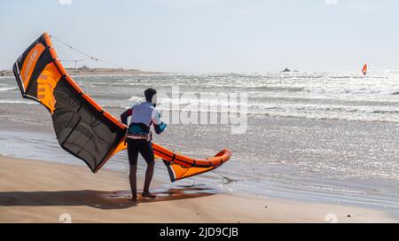 Kitesurfer, der seinen Kite bei starkem Wind an der Atlantikküste im Hafen von Essaouira, Marokko, verwaltet Stockfoto