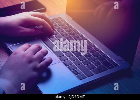 Nahaufnahme der Hände beim Tippen auf dem Laptop mit blauem Licht. Geschäfts- und Finanzkonzept. Technologie-Tastatur mit Kopierplatz. Stockfoto