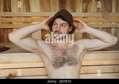 Der Mann sitzt in der Holzsauna Stockfoto