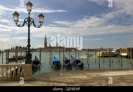 Venedig, Gondeln oder Gondeln, Straßenbeleuchtung und Wahrzeichen der Kirche San Giorgio Maggiore im Hintergrund. Italien, Europa. Stockfoto