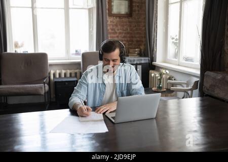 Mann, der das Schreiben auf dem Copybook während des Distanzierungsskurs über Videocall studiert Stockfoto