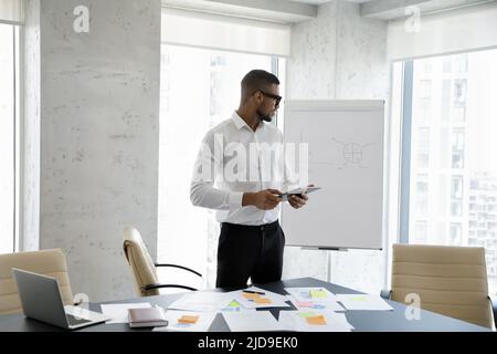 Der junge afrikanische Geschäftsmann nutzt ein digitales Tablet, das im Sitzungssaal des Büros arbeitet Stockfoto