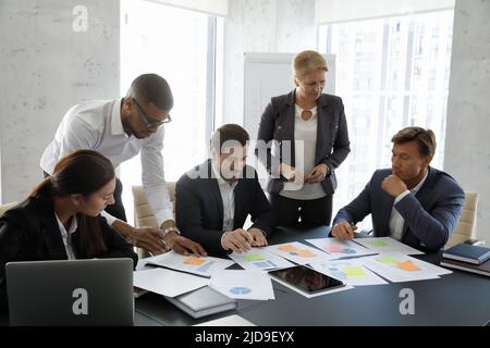 Die im Sitzungssaal versammelten Teamkollegen führen während des Briefings eine Überprüfung der Finanzstatistiken durch Stockfoto