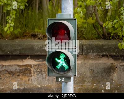 Ampel für Fußgänger, die ein GO-Symbol für das Überqueren der Straße zeigt. Ein grün beleuchteter Lauffigur ist das Signal zum Starten. Stockfoto