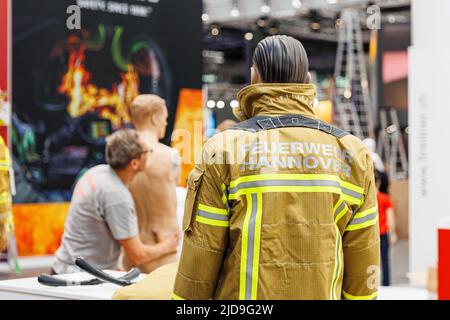 Hannover, Deutschland. 19.. Juni 2022. Ein Ausstellungsdummy steht auf einem Messestand und trägt eine Feuerwehrjacke mit der Aufschrift 'Feuerwehr Hannover'. Die Interschutz ist die Weltleitmesse für Feuerwehr, Rettung, Katastrophenschutz und Sicherheit und findet vom 20. Bis 25. Juni in Hannover statt. Kredit: Michael Matthey/dpa/Alamy Live Nachrichten Stockfoto