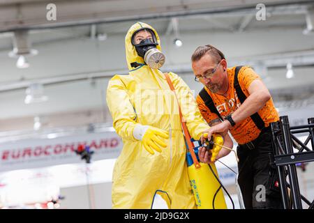 Hannover, Deutschland. 19.. Juni 2022. Ein Mitarbeiter bereitet eine Schaufensterpuppe mit CBRN-Schutzanzug vor. Die Interschutz ist die Weltleitmesse für Feuerwehr, Rettung, Katastrophenschutz und Sicherheit und findet vom 20. Bis 25. Juni in Hannover statt. Kredit: Michael Matthey/dpa/Alamy Live Nachrichten Stockfoto