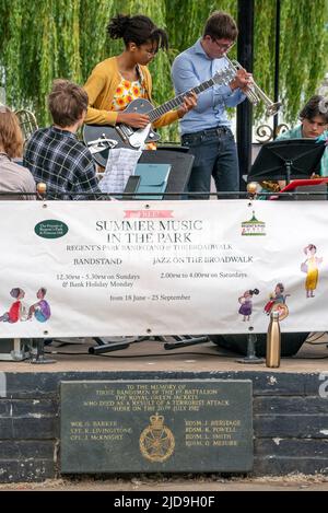 Regent's Park, London, Großbritannien. 19.. Juni 2022. Am 19. Juni 2022 wird das National Youth Jazz Orchestra (NYJO) rund um den Bandstand im Regent's Park im Zentrum von London zu einem Publikumsmagnet. Das Festival wird an Sonn- und Feiertagen bis zum 2022. September fortgesetzt. Die Orchestermitglieder Inshira (Gitarre) und Benedict (Trompete) spielen auf dem Bandstand über einer Gedenktafel an sieben Bandmitglieder der Royal Green Jackets, die im nächsten Monat vor 40 Jahren bei einem Bombenangriff der IRA auf diesen Bandstand starben. Kredit: Rob Taggart/Alamy Live Nachrichten Stockfoto