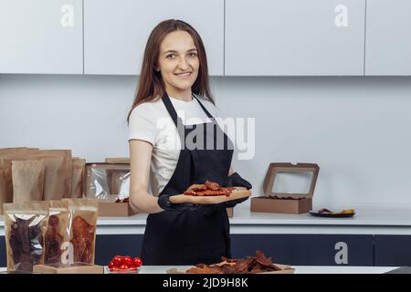 Mädchen hält Fleisch auf einem Tablett auf einem hellen Hintergrund Stockfoto