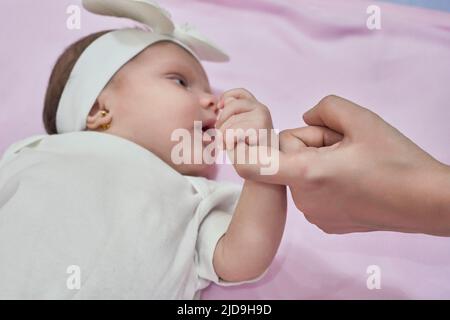 Nahaufnahme der schlafenden Babyhand in der Hand der Mutter auf dem Bett. Neues Familien- und Babyschlafkonzept Stockfoto